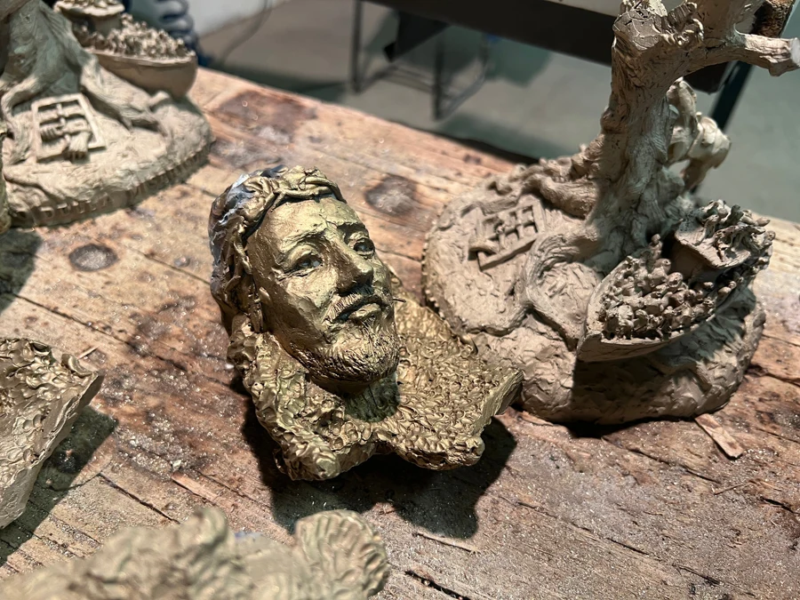 Il banco da lavoro dell'artista, con le formelle in gesso prima della fusione.
