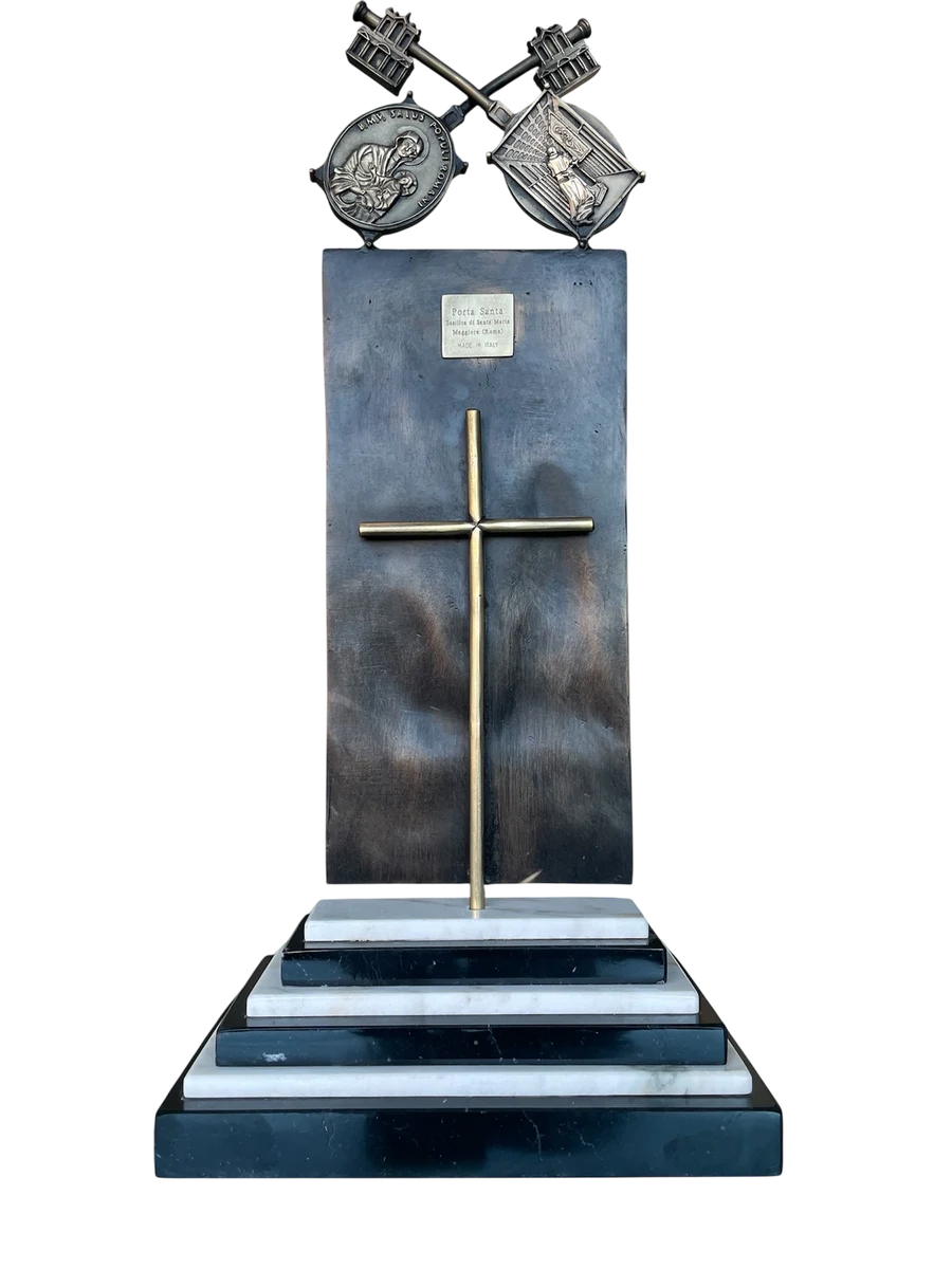 Il retro dell'opera: la croce, la targa identificativa della Porta Santa e il basamento a gradoni bianchi e scuri.